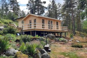 caseta de jardín de color natural cercado con pinos y jardín paisajista