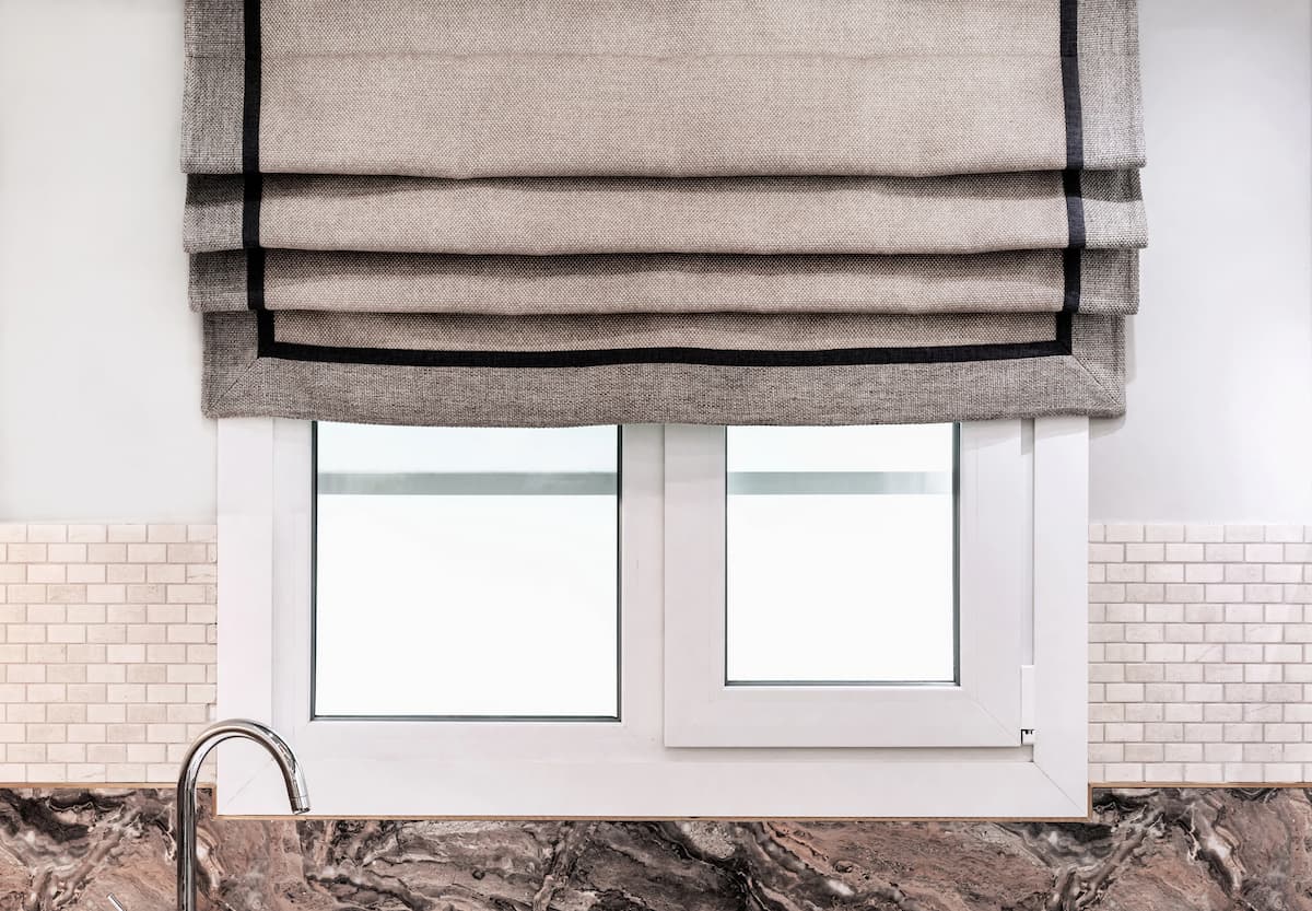 Fragmento de la moderna ventana de plástico con persianas venecianas blancas
